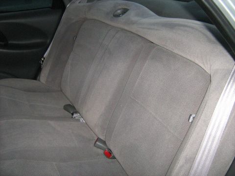 1988 Mercury Grand Marquis - The interior of a car shows a gray fabric rear seat with seat belts and a headrest speaker.