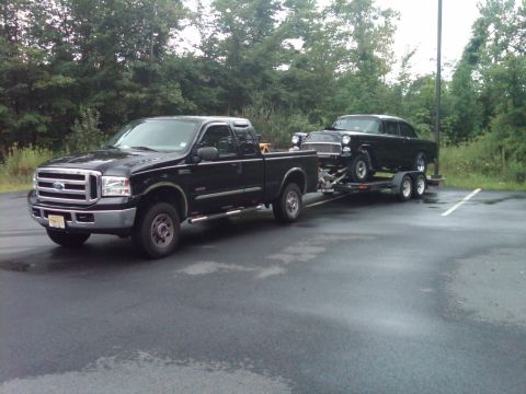 1955 Chevrolet Bel Air - A black 1955 Chevrolet Bel Air is transported on a trailer pulled by a black Ford pickup truck.