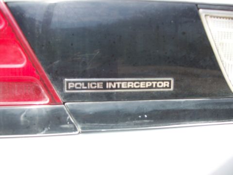 2004 Ford Crown Victoria - Close-up of a POLICE INTERCEPTOR badge on the rear of a dark-colored vehicle.