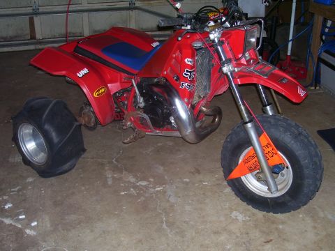 1991 Ford Bronco - A red three-wheeled ATV is parked indoors, showing its sand tire and front wheel with a sale tag.