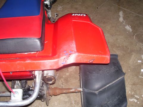 1991 Ford Bronco - Close-up of a red ATV's rear fender and seat, showing some scuffs and marks.