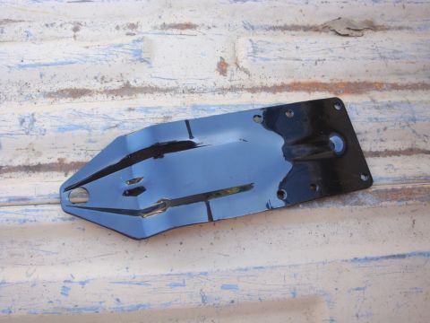 1988 Ford F-350 - A black metal bracket with a complex shape and several mounting holes is shown against a weathered surface.
