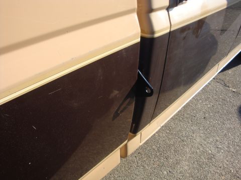1988 Ford F-350 - A side view of a two-tone brown and tan truck door shows a black bracket mounted near the door seam.