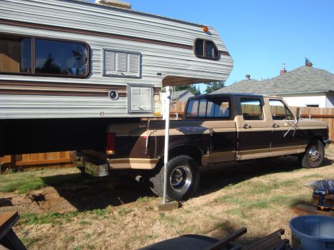 1988 Ford F-350 - Ford pickup truck with a camper shell parked in a backyard on a sunny day.