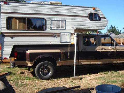 1988 Ford F-350 - A two-tone brown and tan pickup truck is fitted with a large camper, parked outdoors on a sunny day.