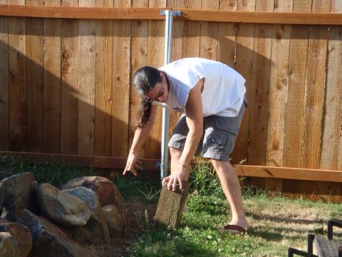 1988 Ford F-350 - A person is working in a grassy yard near a wooden fence, holding a piece of wood.