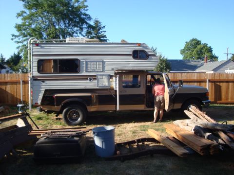 1988 Ford F-350 - A person enters a two-tone brown and tan truck camper parked in a grassy yard.