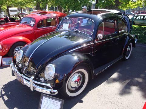 1964 Ford Fairlane - A black Volkswagen Beetle is displayed at a show next to a red Beetle.
