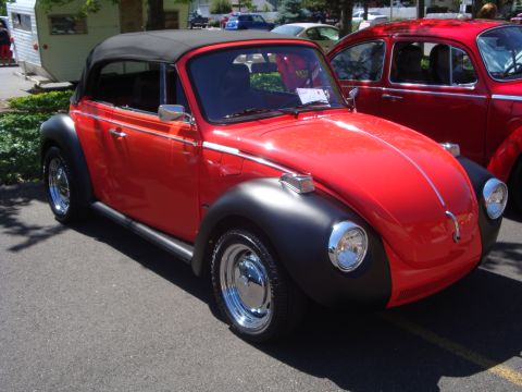 1964 Ford Fairlane - A red convertible Volkswagen Beetle is parked next to another red Volkswagen.