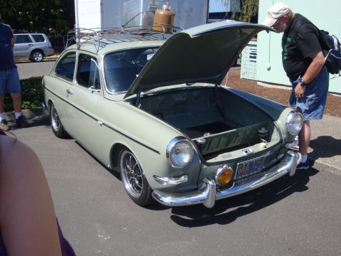 1964 Ford Fairlane - A light green Volkswagen Type 3 Fastback is displayed with its front hood open, a roof rack and a man inspecting the storage area.