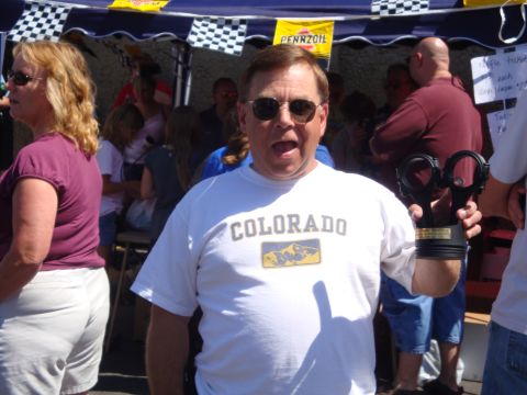 1964 Ford Fairlane - A man proudly displays a trophy shaped like a piston at an outdoor event.