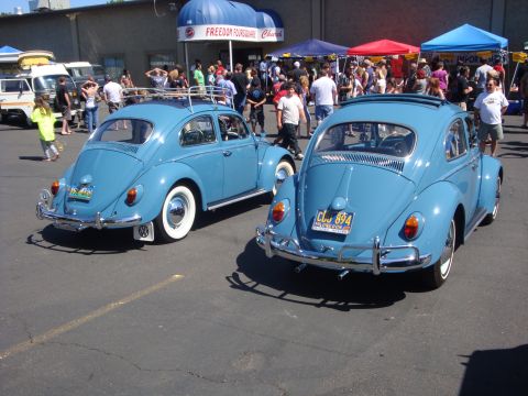1964 Ford Fairlane - Two classic blue Volkswagen Beetles are displayed at an outdoor event.