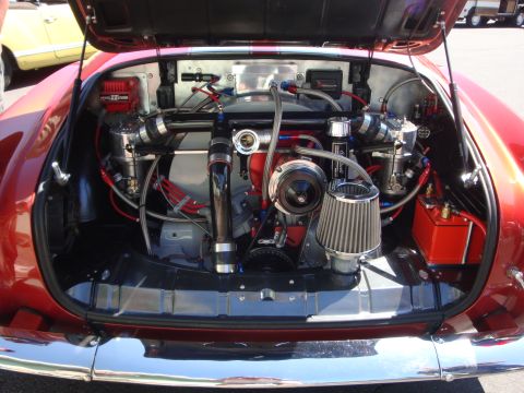 1964 Ford Fairlane - Customized engine bay with twin turbos and extensive plumbing is visible in the rear of a red vehicle.
