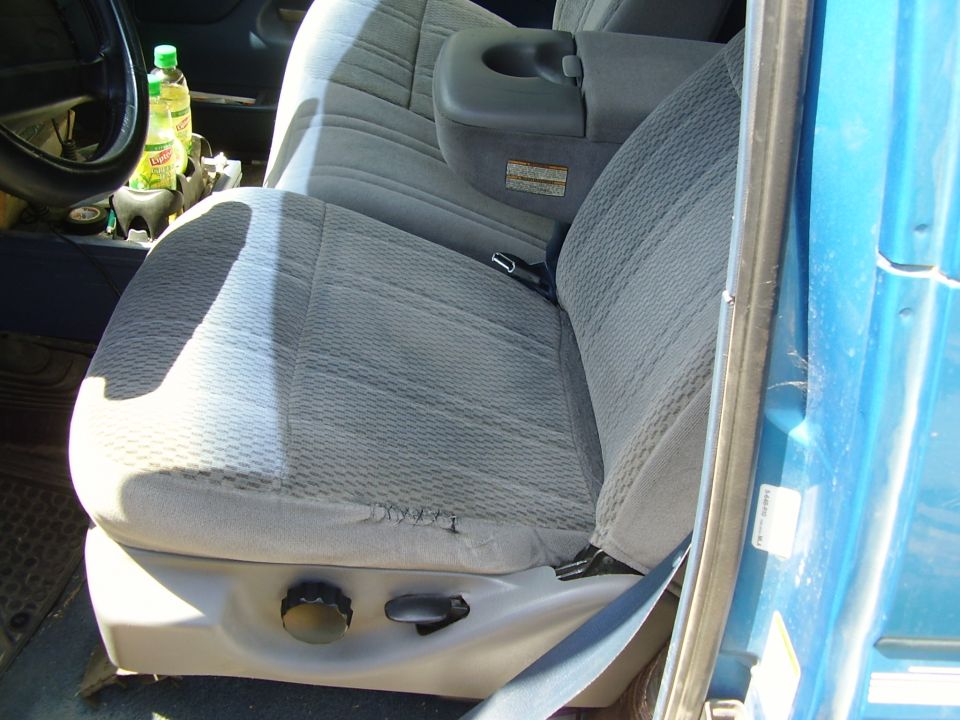 1995 Ford Bronco interior showing gray patterned cloth seats, center console with cup holder, and blue exterior door panel