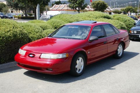 1990 Ford Taurus - This red sedan features a sunroof and a distinctive body style from the mid-1990s.
