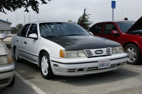 1990 Ford Taurus - White 1990 Ford Taurus sedan with a black hood, parked outdoors.