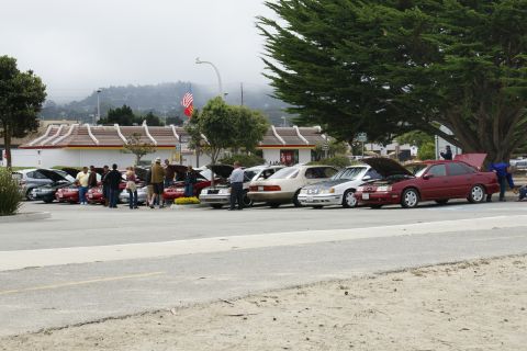 1990 Ford Taurus - Cars gathered at a meet, with a 1990 Ford Taurus among them, near a McDonald's.