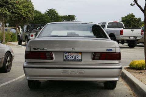 1990 Ford Taurus - Rear view of a 1990 Ford Taurus SHO, with other vehicles in the background.