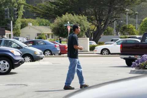 1990 Ford Taurus - A blue sedan is parked on the street as a man walks across the road.