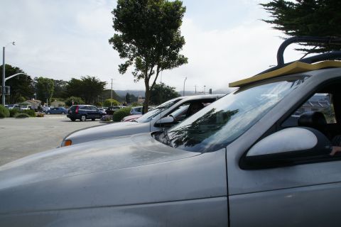 1990 Ford Taurus - Several vehicles are parked in an outdoor lot under a cloudy sky.