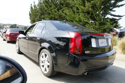 1990 Ford Taurus - Black sedan with vertical taillights seen in traffic, with a red sedan behind it.