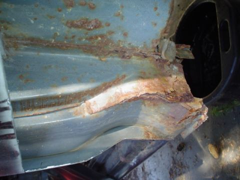 1988 Ford Bronco - This close-up shows significant rust damage on a vehicle's metal panel, obscuring any identifying features.