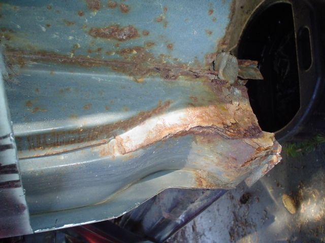 Heavily rusted metal panel, likely from a vehicle's undercarriage