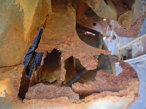 1988 Ford Bronco - Extensive rust has compromised the structural integrity of this vehicle's frame, revealing exposed wiring beneath.