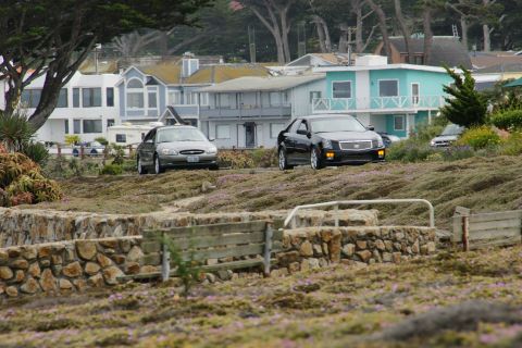 1990 Ford Taurus - Two cars are parked on a hill overlooking houses and trees.