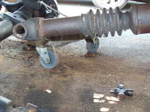 1989 Ford F-150 - Close-up view of a vehicle's driveshaft and a separate U-joint, likely for repair or replacement.