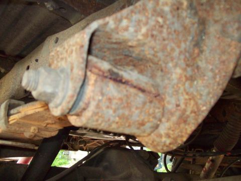 1989 Ford F-150 - Close-up of a heavily rusted leaf spring mount on a vehicle's undercarriage.