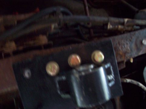 1989 Ford F-150 - Engine bay components, including a black bracket and three gold bolts, are visible with some rust and wiring.