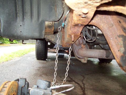 1989 Ford F-150 - Close-up view of a heavily rusted truck frame, with chains attached to the chassis.