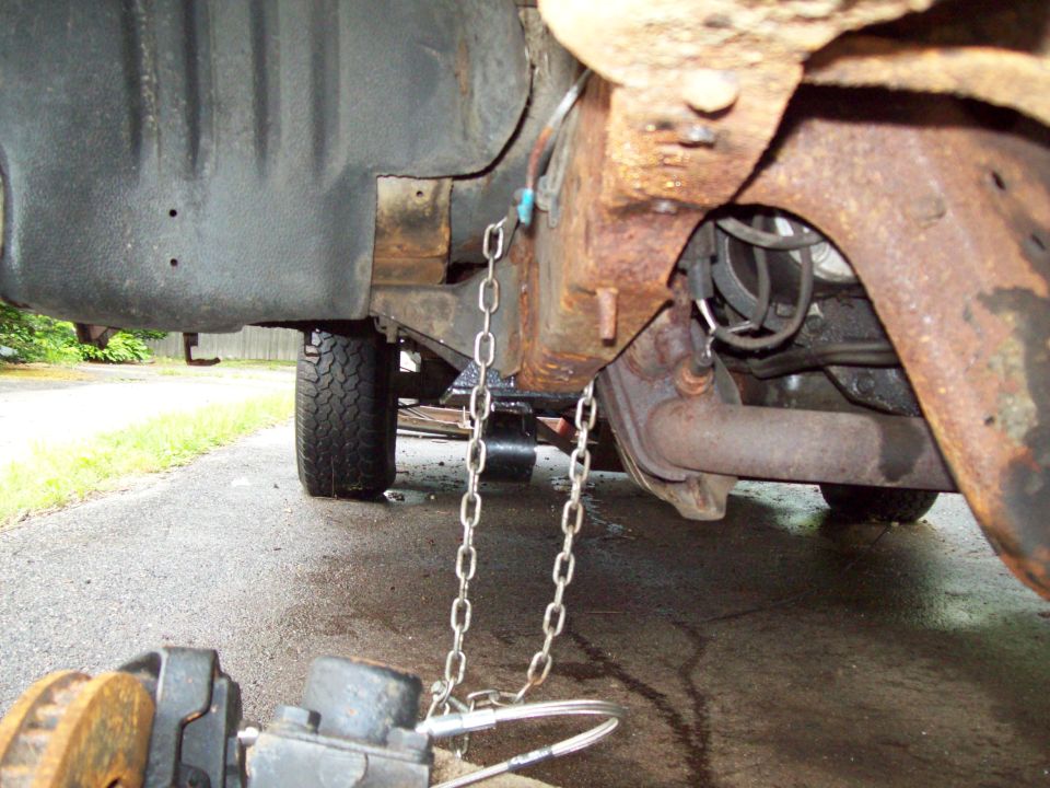 Rusty truck frame with chains hanging from it