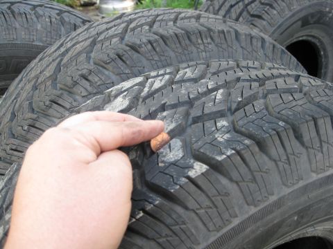 Tires with visible tread wear and a finger pointing to a small object embedded in the tread