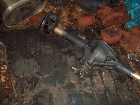1989 Ford F-150 - A disassembled rear axle assembly, complete with a disc brake, is shown on a cluttered floor.