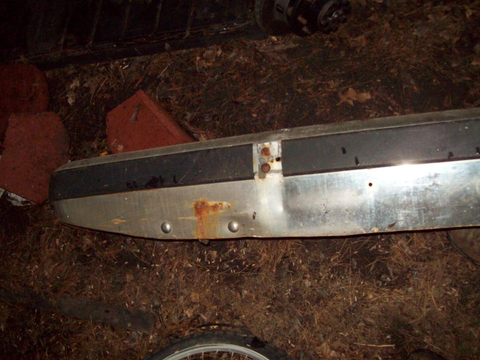 Chrome and black truck bumper with rust spots, lying on the ground