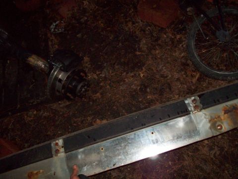 1989 Ford F-150 - Close-up of a vehicle axle and wheel hub assembly lying on the ground.