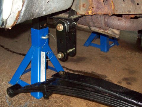 1989 Ford F-150 - A vehicle's undercarriage is supported by jack stands during a suspension modification.