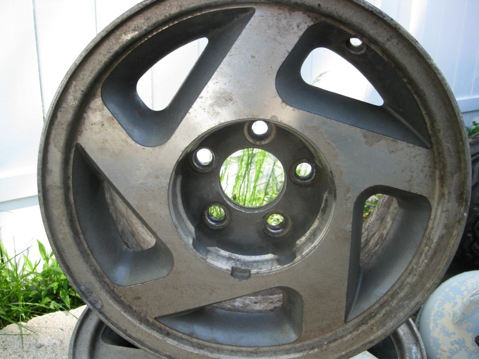 Aluminum wheel with five spokes and a silver finish, showing some wear and dirt