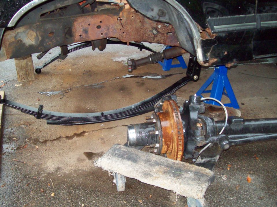Truck rear axle assembly with leaf springs removed, supported by jack stands