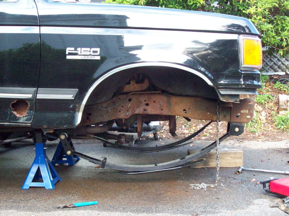 Black 1989 Ford F-150 with front end jacked up, showing rusty frame and leaf springs
