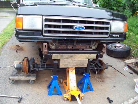 1989 Ford F-150 - Front end of a black Ford truck undergoing repairs, supported by jack stands and a hydraulic jack.