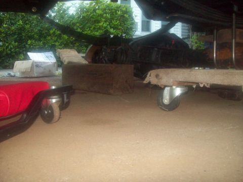 1989 Ford F-150 - The underside of a vehicle is visible, supported by a creeper and wooden blocks.
