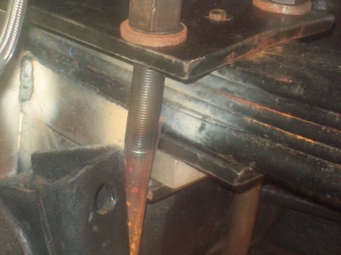 1989 Ford F-150 - A close-up view of a rusty bolt and metal plate, part of a vehicle's suspension system.