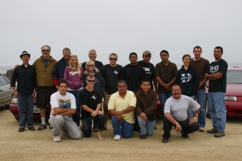 1990 Ford Taurus - A group of people gathered for a photo, with a red vehicle partially visible behind them.