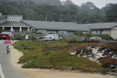 1990 Ford Taurus - Two cars and a building are visible in this coastal scene with a person on a bicycle.