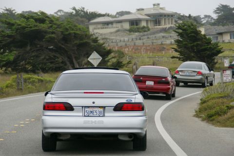 1990 Ford Taurus - Silver 1990 Ford Taurus seen from behind on a road with other vehicles.