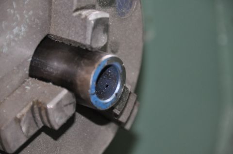 1996 Ford Bronco - Close-up of a metal part with a blue ring, secured in a lathe chuck for machining.