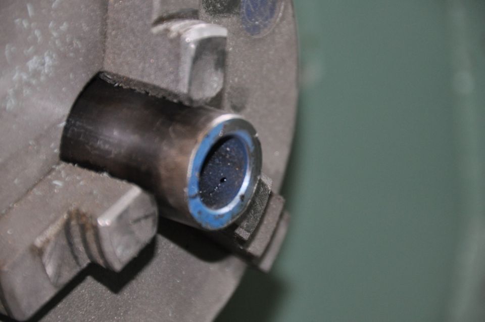 Metal part with blue ring held in lathe chuck